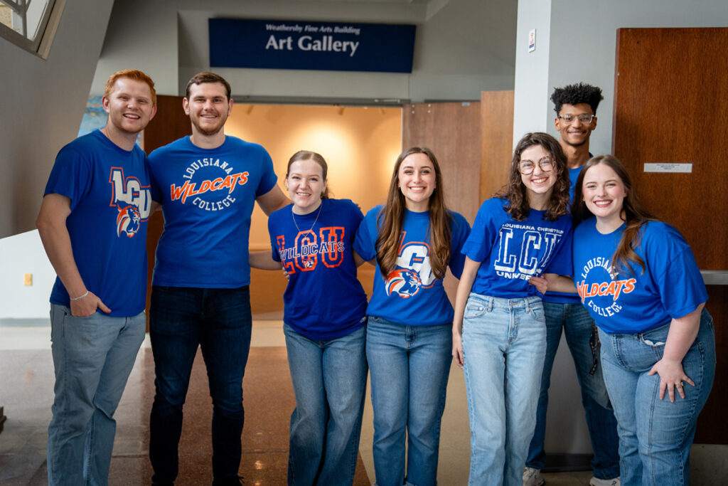 Seven smiling students in blue Louisiana