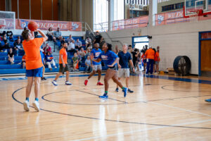 Man in orange shirt shoots a basketball
