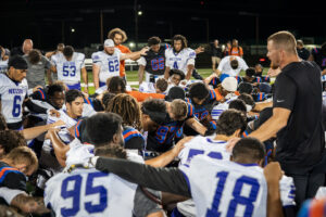 Football team huddles on field at