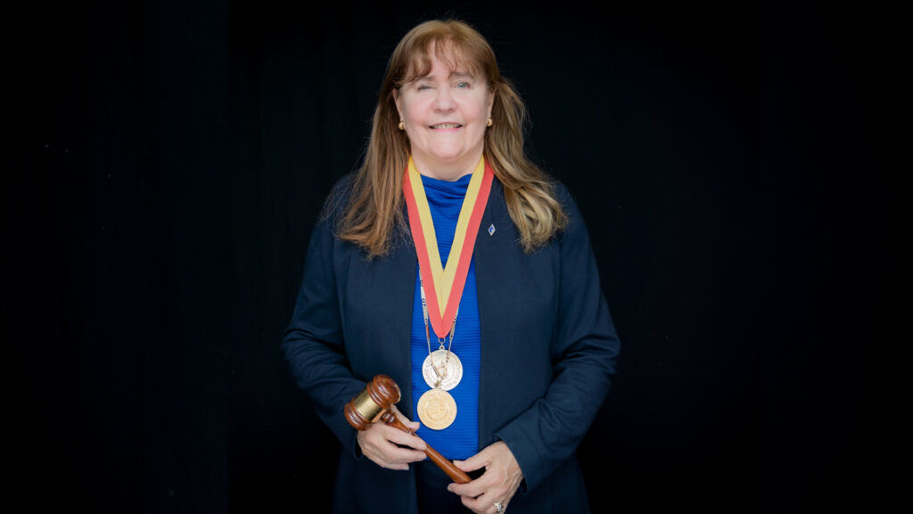 Dr. Marcia Hardy on a black background with gavel and pendents notating her recent honors induction.