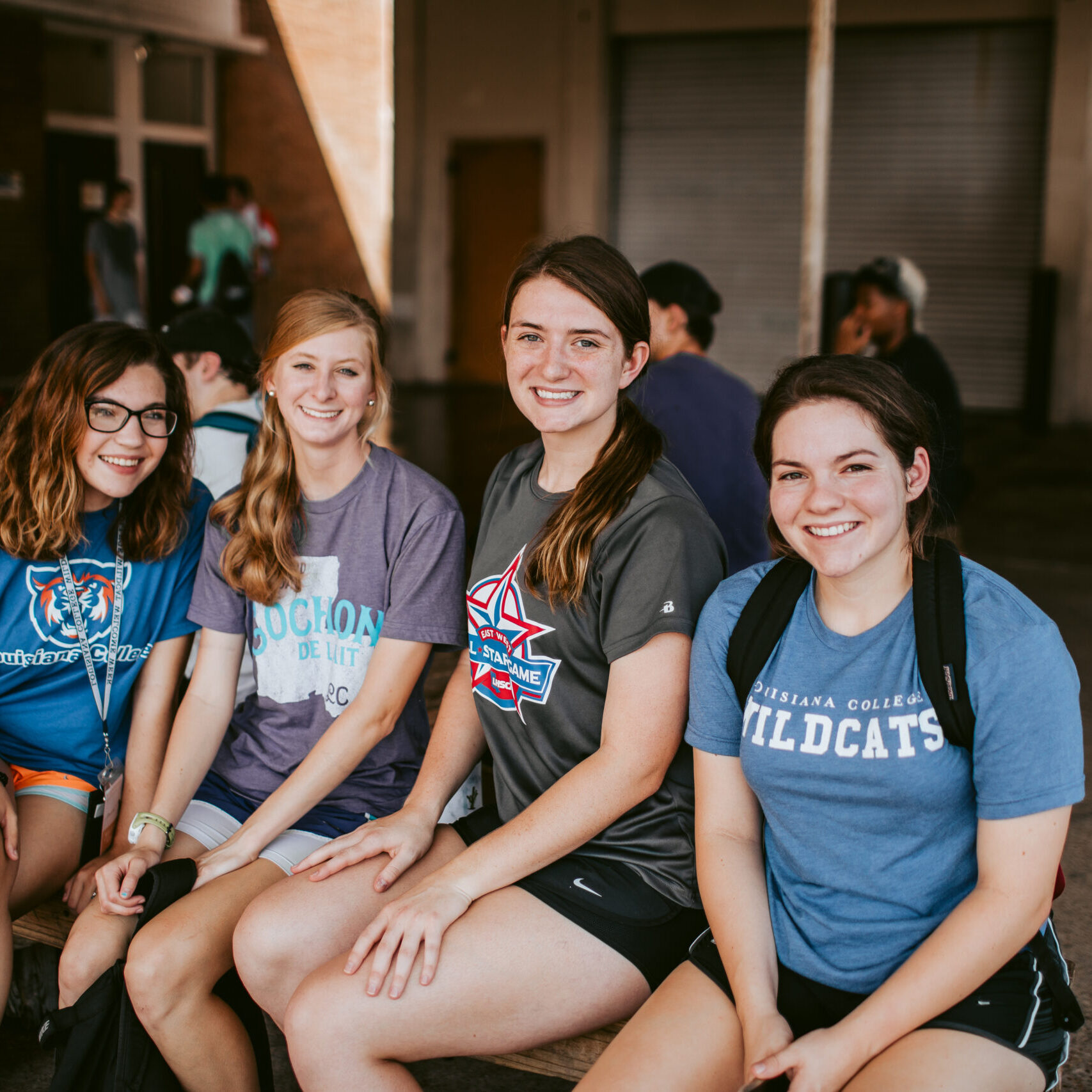 Four smiling young women in t-shirts